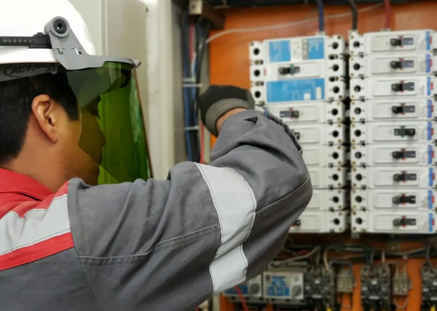 Técnico revisando un tablero eléctrico con su equipo de protección.